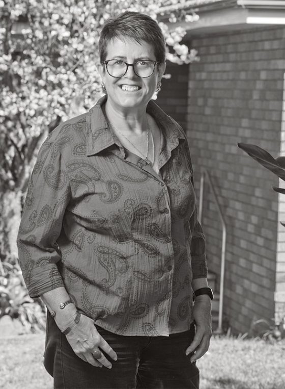 Black and white portrait of Kate, standing outside her home in Toongabbie for Fine Photography's COVID vaccination campaign 'Our Call to Arms'.